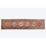 A long Oriental woolen runner with geometric motifs and floral design, 20th C.