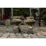 A pair of stone garden vases on square bases, one dated 1873