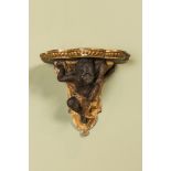 A partly gilt and patinated wooden wall bracket with an atlant, probably Italy, 18/19th C.