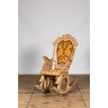 A richly carved wooden rocking chair with snake-shaped legs, 20th C.