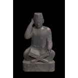 A basalt sculpture of a reading student, Indonesia, 20th C.