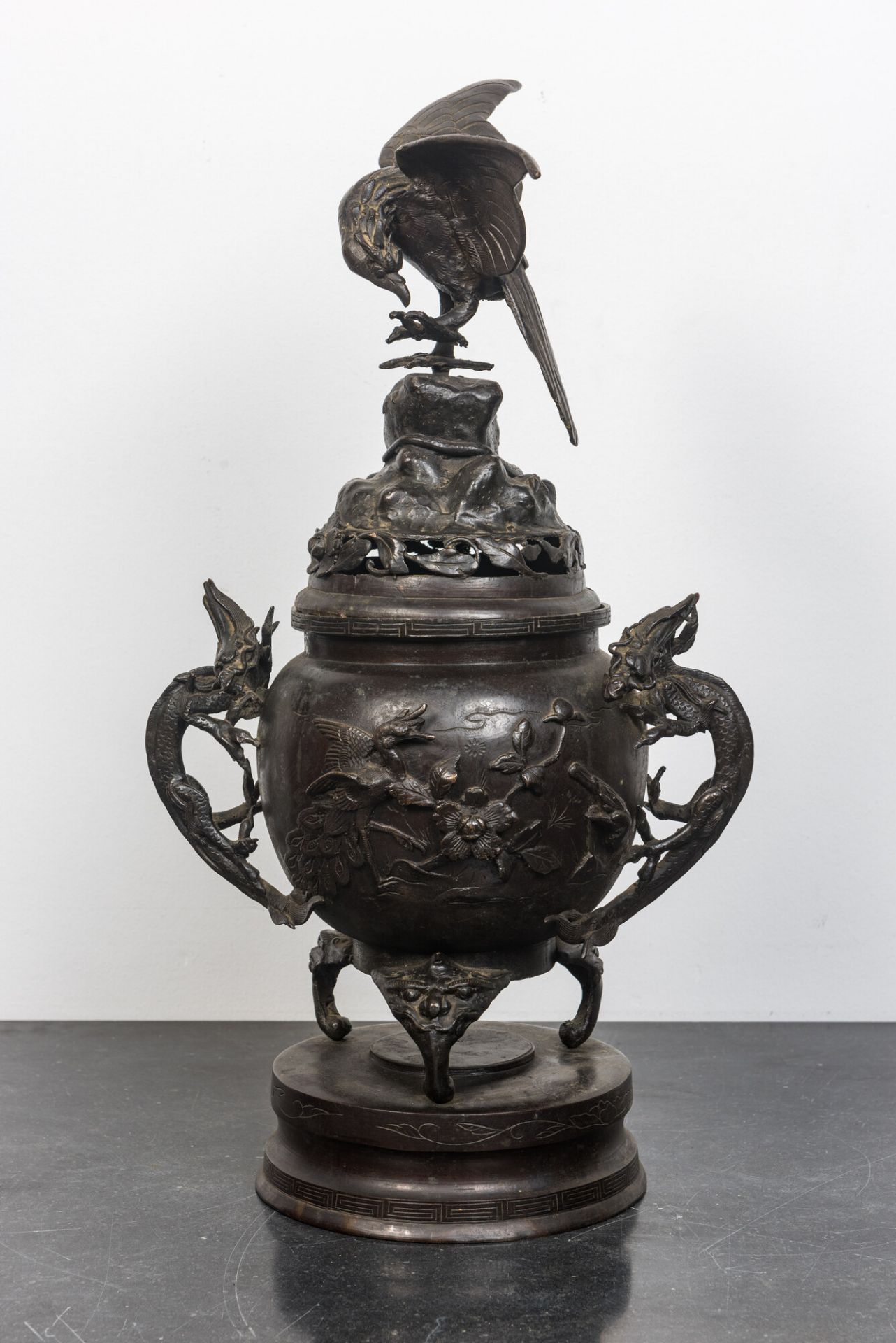 A large Japanese patinated bronze koro on stand with birds, dragons and blossoming branches, Meiji,
