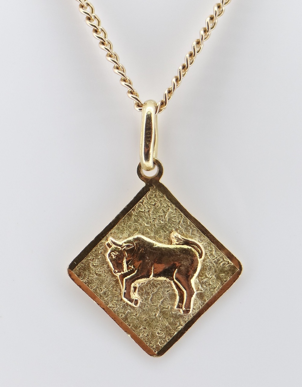 YELLOW METAL BULL PENDANT, indistinctly hallmarked, on 10k gold chain measuring 64cms, 12.6gms