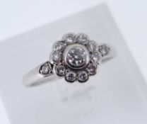 WHITE METAL DIAMOND CLUSTER RING, the central stone measuring 0.15cts approx., surrounded by a