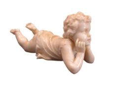 VICTORIAN CARVED IVORY FIGURINE OF A CHILD - depicted lying on its stomach with its head supported