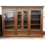 LARGE CARVED OAK BOOKCASE having detail to the frieze over four glazed doors and interior adjustable