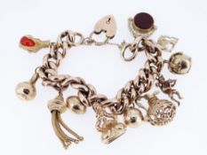 9CT GOLD CHARM BRACELET, the curb link chain with heart shaped padlock, having an assortment of