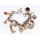 9CT GOLD CHARM BRACELET, the curb link chain with heart shaped padlock, having an assortment of