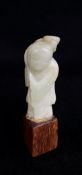 CHINESE CELADON JADE CARVING OF A BOY, holding a flowering lotus branch, hadwood base, overall 10cms