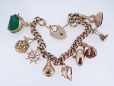 9CT GOLD CHARM BRACELET, the curb link chain with heart shaped padlock, having an assortment of nine