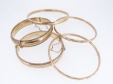 FIVE 9CT GOLD BANGLES comprising two engraved examples with maker’s mark RPH, together with three