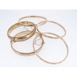 FIVE 9CT GOLD BANGLES comprising two engraved examples with maker’s mark RPH, together with three