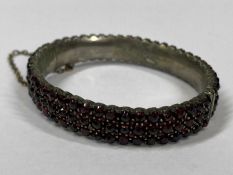 VINTAGE THREE ROW GARNET BANGLE IN WHITE METAL - with gilt metal safety chain, 6.5cms across