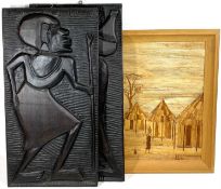 CARVED AFRICAN EBONISED PANELS and a straw work picture of an African type village, 63 x 32cms the