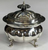 AN OVAL SILVER TEA/SUGAR CADDY - with single hinged lid and on four scrolled supports, fine clear