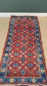 EASTERN RUG - central red ground with repeating traditional pattern and multi bordered edge, hand