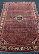 HAMADAN VILLAGE RUG, allover geometric red field with central lozenge medallion, floral ivory border