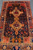 NAVAHAN TRIBAL RUG, double lozenge medallion on a blue abrash field, stylised vine border, 260 x