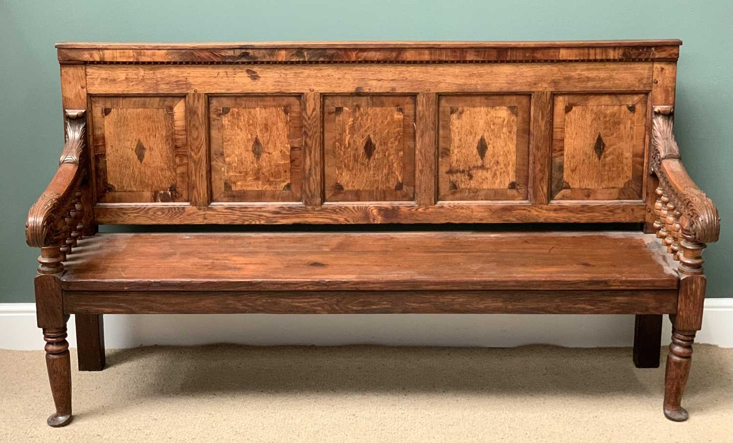19th CENTURY OAK BENCH with a five fielded panel back, carved arms with bobbin supports, on turned