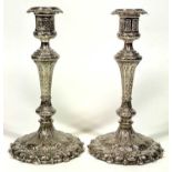 EPNS CANDLESTICKS, A PAIR - having profuse decoration in relief on circular petal form bases with