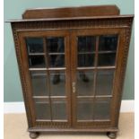 ANTIQUE OAK BOOKCASE CUPBOARD with two sectional panelled glazed doors, railback top and on bun