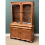 ANTIQUE PINE BOOKCASE CUPBOARD having two glazed doors over a base with central drawer and