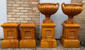 TWO TREACLE GLAZED CAMPANA VASES, on foliate square section bases, together with two additional