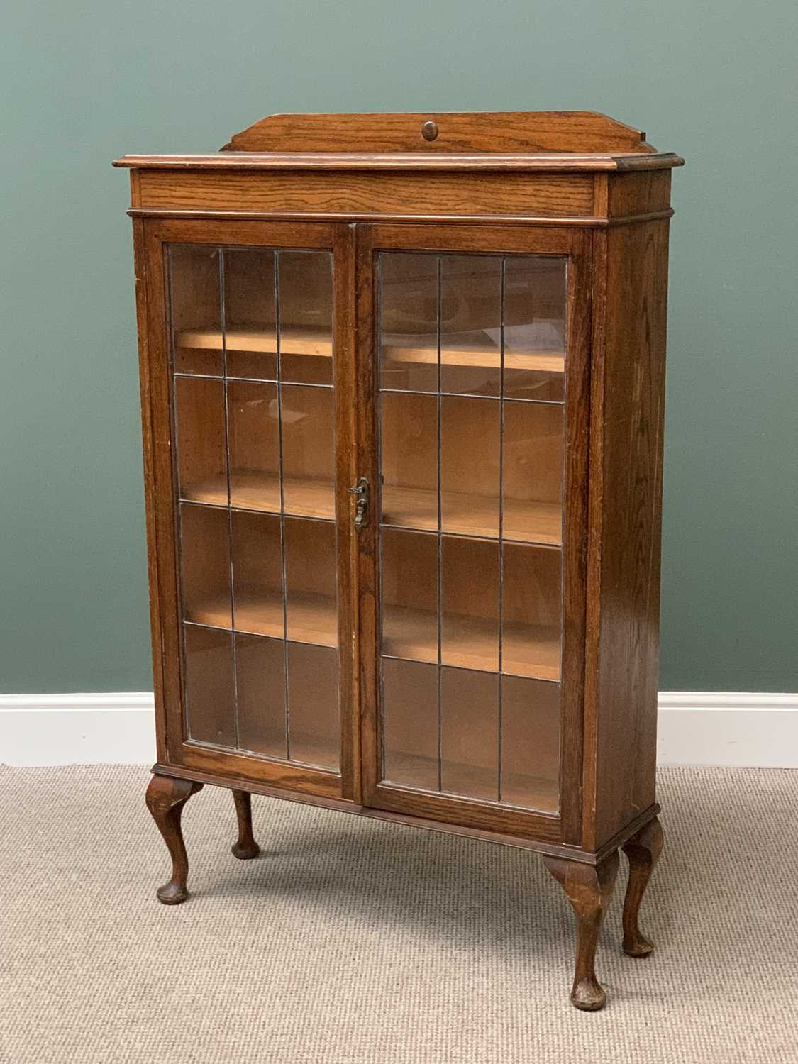 POLISHED OAK BOOKCASE CUPBOARD with railback top, twin leaded glass doors, on queen anne supports,