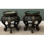 CARVED EBONIZED & GILT HIGHLIGHTED CHINESE STANDS, baize covered circular tops with carved detail in