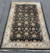 ORIENTAL RUG BY G H FRITH, black ground with traditional floral pattern and wide bordered cream