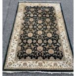 ORIENTAL RUG BY G H FRITH, black ground with traditional floral pattern and wide bordered cream