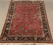 EASTERN STYLE WOOLLEN RUG with tasselled ends, red ground with blue multi-border, the central