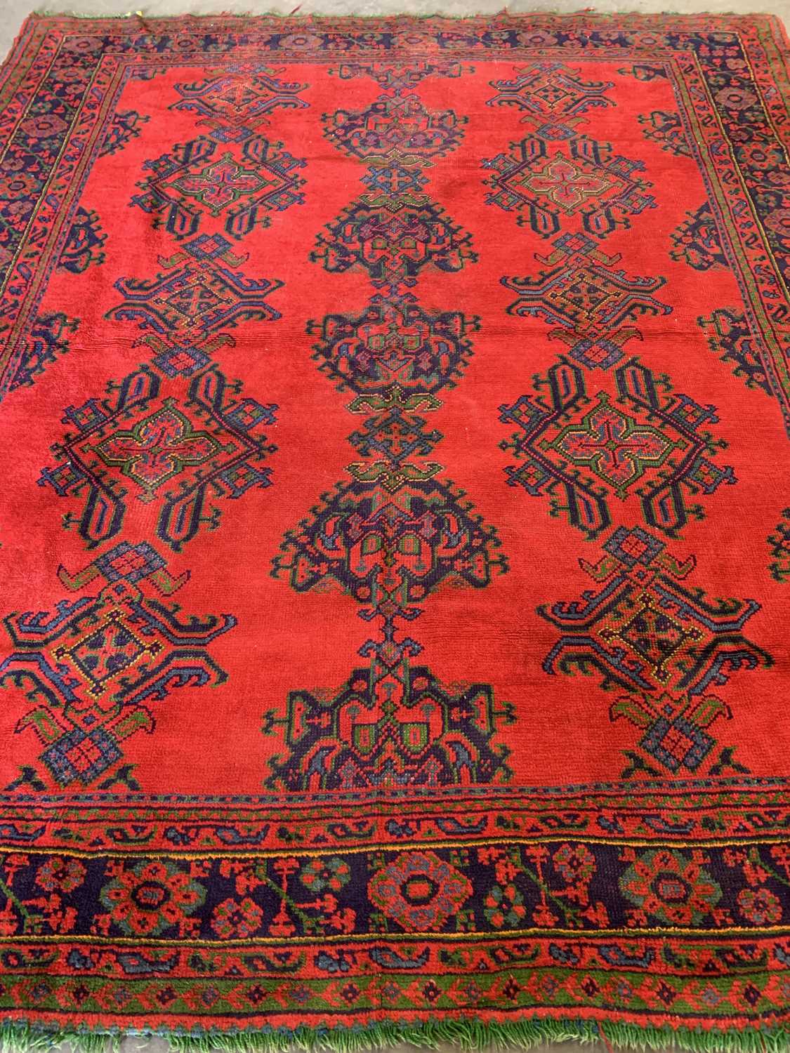 EASTERN STYLE WOOLLEN RUG, red ground with blue border and central repeating pattern, 341 x 294cms