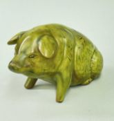 EWENNY POTTERY MODEL PIG raised over front legs, green glaze, loin inscribed 'Y Mochyn Bach', signed