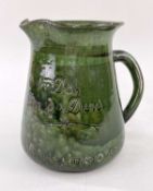 EWENNY POTTERY WHISKY JUG of tapered form having a curvaceous loop handle, in deep green mottled