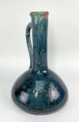 EWENNY POTTERY JUG mottled green-blue glaze, long neck, applied loop handle, sgraffito insribed with