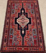 EASTERN WOOLEN RUG, red ground with multi pattern border and central diamond motif, 147 x 91cms