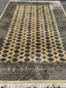 LARGE WOOLLEN RUG with tasselled ends, yellow ground, multi-pattern border and repeating circular