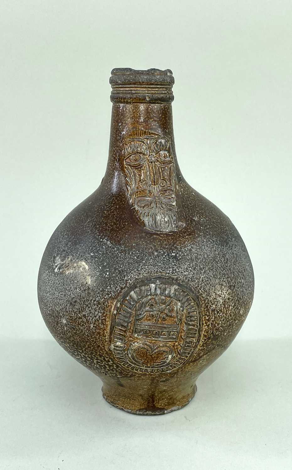 17TH CENTURY GERMAN STONEWARE BELLARMINE, decorated with mask and coat of arms, strap handle,