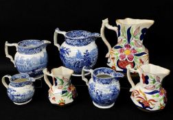GROUP OF SEVEN SWANSEA POTTERY JUGS including graduated trio of twig-handled jugs, painted in the