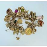 9CT GOLD CURB LINK CHARM BRACELET having heart shaped padlock, approximately thirty charms in mainly