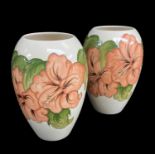 MOORCROFT POTTERY comprising two white ground ovoid vases, both with tube-lined Hibiscus decoration,