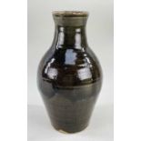 A STUDIO POTTERY STONEWARE VASE of baluster form with narrow neck flared at rim, in deep brown-green