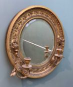 VICTORIAN OVAL GILTWOOD & GESSO GIRANDOLE MIRROR, with moulded leaf and berry frieze, the sides