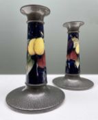 MOORCROFT FOR LIBERTY: PAIR TUDRIC CANDLESTICKS, c. 1910, in the 'Wisteria' pattern, hammered pewter