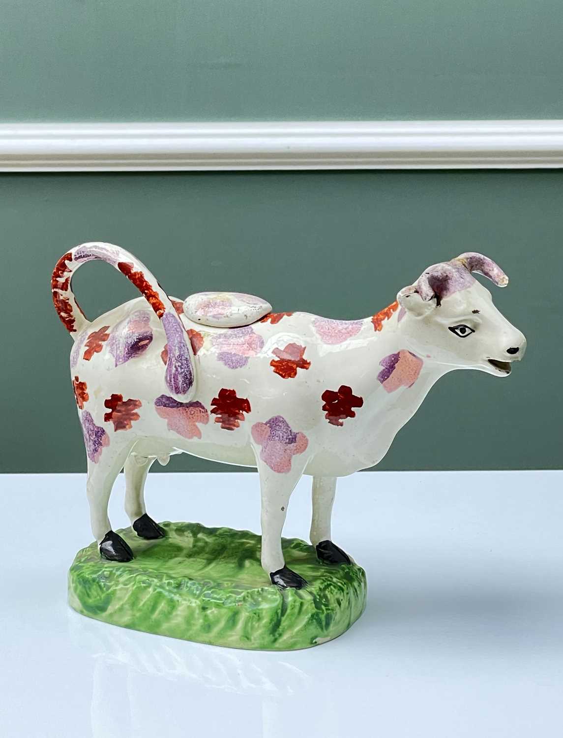 SWANSEA POTTERY COW CREAMER with pink lustre and red mottled markings, moulded base in bright