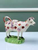 SWANSEA POTTERY COW CREAMER with pink lustre and red mottled markings, moulded base in bright