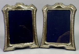 PAIR OF ELIZABETH II SILVER FACED PHOTOGRAPH FRAMES, with shaped tops and embossed decoration,