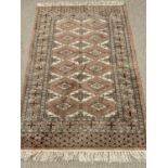 EASTERN TYPE RUG - terracotta ground with tasselled ends, wide bordered edge and repeating diamond
