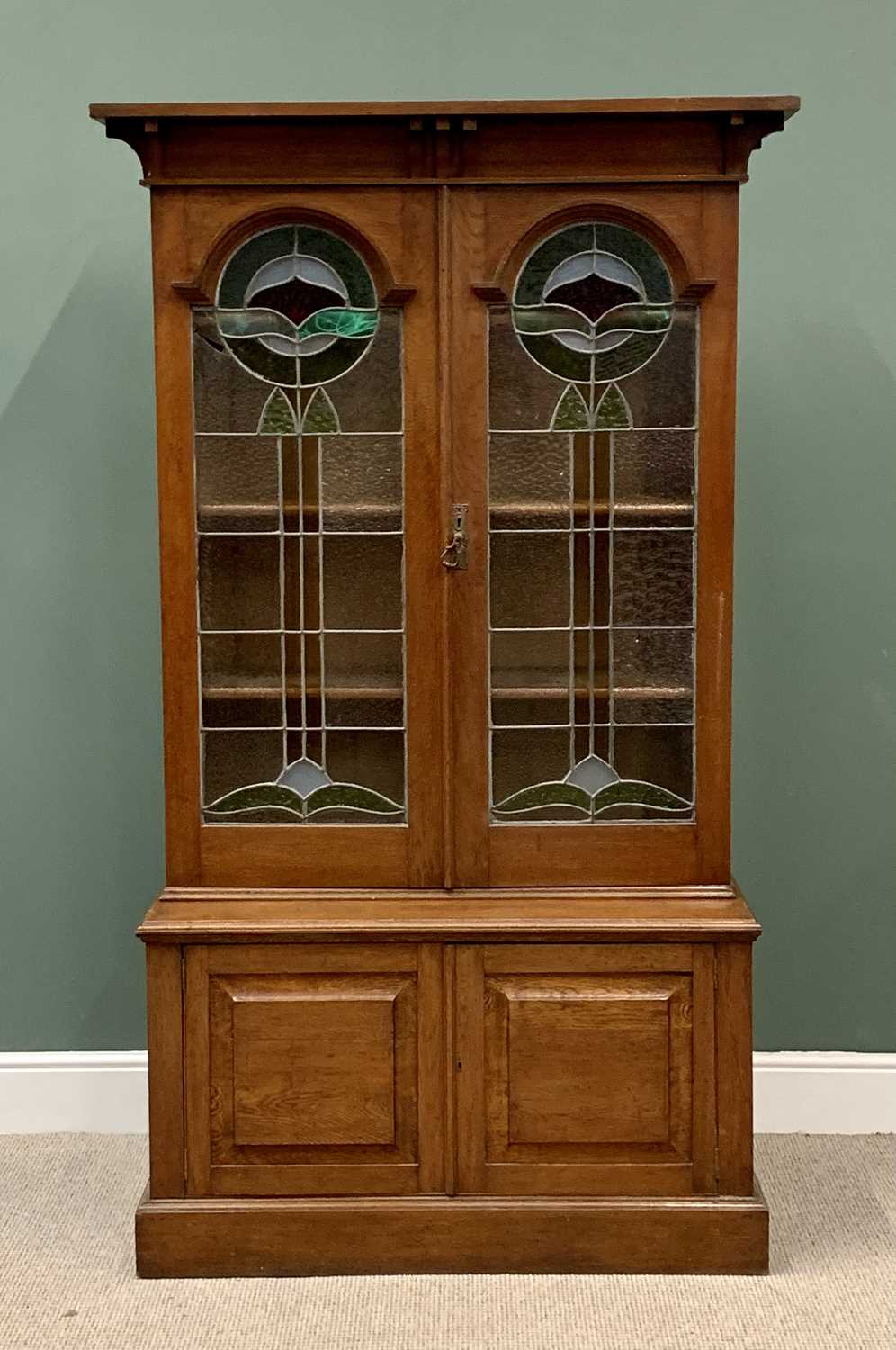 ARTS & CRAFTS STYLE OAK BOOKCASE CUPBOARD, the upper section with twin leaded and colour stained